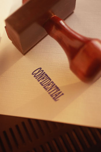 file folder with the word confidential stamped on it. The stamp is lying on the folder.